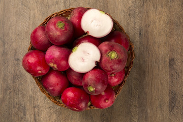 Some radishes in a basket over a wooden surface