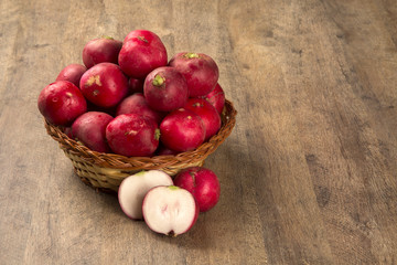 Some radishes in a basket over a wooden surface