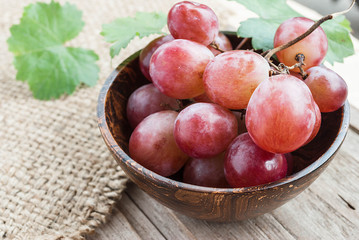 Red grape in wooden bowl on wooden table
