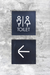 Fototapeta premium Unisex restroom or Toilet and arrow sign on concrete wall style