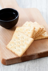 Stack of crackers and tea cup on wooden plate