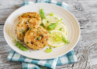 chicken cutlets with lemon and herbs on a white plate on a dark wooden background