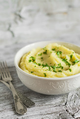 mashed potatoes in a white bowl on a light wooden background