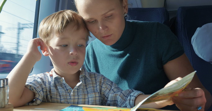 Son and mother with pictured book in train