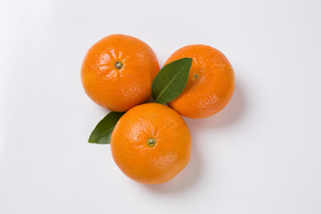 Some tangerines in a basket over a wooden surface