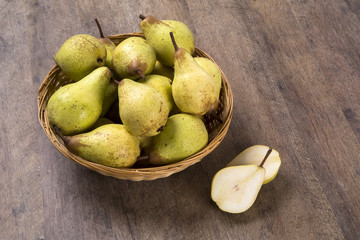 Some pears in a basket over a wooden surface seen from above