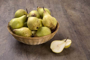 Some pears in a basket over a wooden surface seen from above