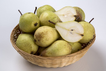 Some pears in a basket over a wooden surface seen from above
