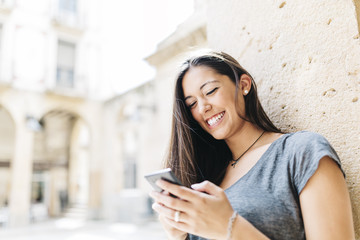 Young smiling woman text messaging on mobile phone