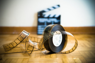 Cinema film reel and out of focus movie clapper board