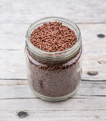 Chocolate sprinkle confetti in a mason jar over rustic aged wooden background