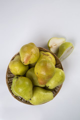 Some pears in a basket over a wooden surface seen from above