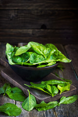 Fresh spinach in bowl on wooden background