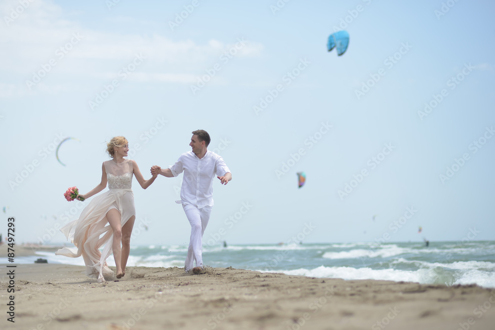 Wall mural running wedding couple on beach