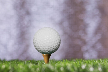 Golf ball on a tee peg bokeh background silver.