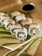 maki sushi with eel, avocado and soy sauce on wooden board and chopsticks