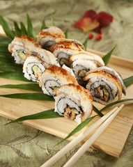 maki sushi with double eel and avocado on wooden board with chopsticks