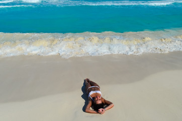 Fototapeta na wymiar Girl lying on the sea beach in a white bikini
