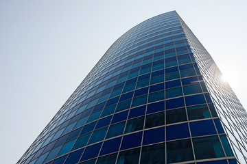 Fototapeta na wymiar Blue glass modern business center with sun behind