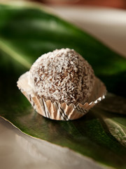 chocolate handmade dessert truffle. chocolate praline on green banana leaf close up on dark background