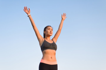 Asian woman raising arms to the sky.