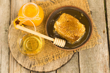 Honey in jar with honeycomb and wooden background.