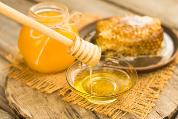 Honey in jar with honeycomb and wooden background.