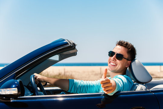 Young man in convertible doing thumbs up.
