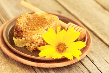 Honey in jar with honeycomb and wooden background.