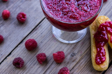 Raspberry jam and fresh raspberry on the wooden table