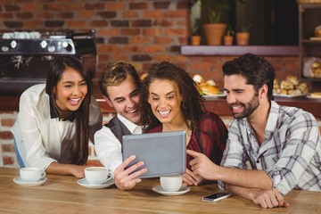 Smiling friends looking at digital tablet 