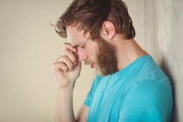 Troubled hipster leaning against wall