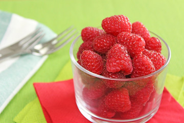 Himbeeren in Schale aus Glas mit grüner Serviette und Besteck - Beeren naschen