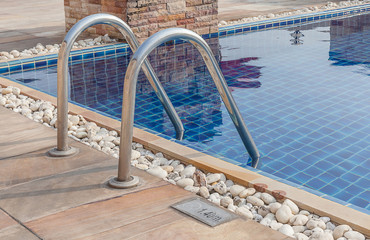 Clear blue swimming pool with steel stair in hotel.