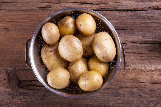 Potatoes in colander shot on a wooden background from above with negative space