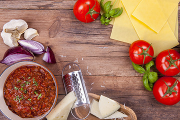 Lasagne ingredients with mince meat in a pan shot on a wooden background from above