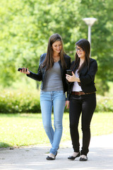 Obraz premium Deux adolescentes se promenant avec leurs téléphones dans un parc