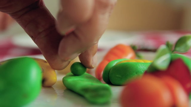 Woman lays with her hand beans made from marzipan in white plate.
Close up shot.