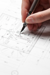 woman holding a pen over a house blueprint