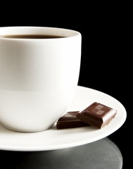 Cup of coffee with chocolate and saucer on black