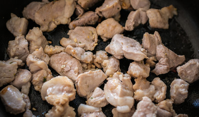 Fried meat with garlic on a pan. Selective focus with shallow depth of field.