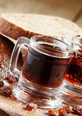 Traditional Russian drink kvass in a mug, with rye bread on a wo