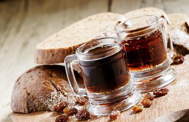 Traditional Russian drink kvass in a mug, with rye bread on a wo