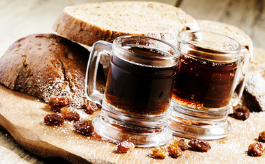 Traditional Russian drink kvass in a mug, with rye bread on a wo