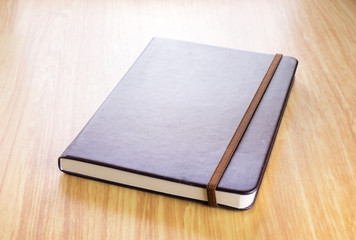 Brown Hard cover notebook with elastic strap on wooden table in