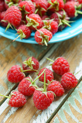 Red raspberry in blue dish on old vintage wooden table.