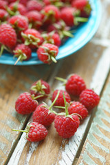 Red raspberry in blue dish on old vintage wooden table.