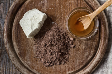 Cocoa butter, cocoa powder and honey on grunge wooden background