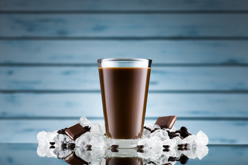 Iced coffee in glass and crushed ice on blue background