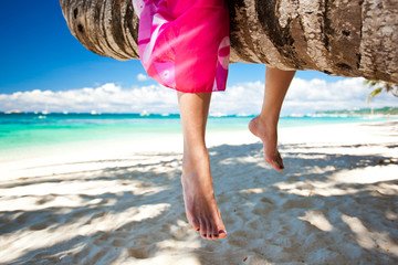 Woman's legs closeup, sitting on coconut palm